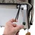 Hand toont hoe een elastische band aan een metalen frame wordt bevestigd. Detailopname van een product met stoffen bekleding en frame.