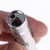 Close-up of a silver laser pointer with red light, held between two fingers.