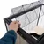 Hand opens the top mesh door of a black cage with wooden platforms inside.