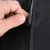 Detailní záběr na ruku otevírající nebo zavírající černý zip na perforovaném materiálu.