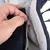 Gros plan sur une main ouvrant une fermeture éclair grise sur un tissu matelassé bicolore noir et gris, montrant la qualité de la fermeture du produit textile.