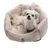 Dog sitting in a beige, fluffy dog bed with Tiaki logo on the front.