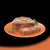 Sliced portion of meat pâté served on an orange plate with fresh herbs, showing product texture and consistency.