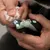 Nahaufnahme einer Person, die mit einem elektrischen Krallenschneider die Krallen einer Katze schneidet. Gerät mit LED-Licht und Schutzabdeckung sichtbar.