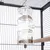 Mangeoire transparente en plastique suspendue dans une cage à oiseaux, compartiments remplis de graines visibles, perchoir en bois à côté.