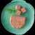 Plate showing a portion of wet pet food with three cut cubes and a sprig of parsley, demonstrating product texture and serving suggestion.