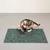 Green mat with Christmas motif and the inscription 'Merry Christmas', with a cat examining the mat.