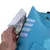 Vue rapprochée d’une main ouvrant une fermeture à scratch sur un manteau bleu pour animal, détails réfléchissants visibles et écusson avec tête de chien.