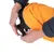 Main ajustant la patte d’un petit chien noir portant un manteau orange avec cordon visible, gros plan sur l’habillage de l’animal.