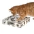 Chat roux utilisant un jeu d’intelligence en bois avec plusieurs ouvertures de formes variées, balle visible à l’intérieur du jouet.