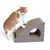 Brown and white cat standing on a scratching furniture with slanted surface and round entrance. Furniture in wood look and cardboard, suitable for scratching and hiding.
