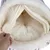 Intérieur d’un tunnel ou sac de couchage pour animal, tissu doux crème, main soulevant l’ouverture pour montrer le coussin moelleux à l’intérieur. Matière visible : tissu peluche.