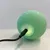 Groene bol met USB-kabelaansluiting, licht groen op. Toont laadfunctie van het product.