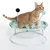 Katzenliege mit Metallrahmen, grünem Stoffbezug und zwei Spielbällen an Federn. Rote Katze sitzt auf der Liege.