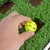 Hand places a yellow plastic ball on a green surface with artificial grass.
