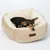 Beiges Hundebett mit weicher Polsterung und Markenetikett 'Modern Living'. Kleiner Hund liegt entspannt im Bett.