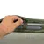 Mano muestra la fijación de una barra metálica gris con cierre de velcro en un bolso verde con material de malla.