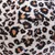 Nærbillede af stofmateriale med leopardmønster i sort, brun og hvid. Synlig søm med overlappende stoflag.
