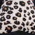 Primer plano de un tejido con estampado de leopardo en negro y naranja sobre fondo blanco.