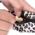 Una mano coloca un snack para perros en forma de hueso en un bolso con estampado de leopardo y cremallera.