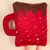 Red plush toy in the shape of a cup with brown foam look and white dots, suitable for pets.