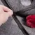 Hand opening a black zip on grey felt material with red plush ball. Close-up of a product with zip function.