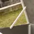 Detailný záber na bielu podpernú ramenu, ktorá drží otvorené veko sivej drevenej konštrukcie.