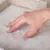 Hand drukt op het zachte, pluizige oppervlak van een lichtkleurig textielmateriaal om de materiaaleigenschappen te illustreren.