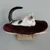Chat allongé sur un coussin rond en tissu bordeaux fixé à une étagère murale en bois clair, support visible sous la plateforme.