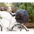 Trasportino nero in tessuto con rete, fissato sul portapacchi di una bicicletta, contiene un piccolo cane visibile all’interno.