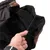 Close-up of a brown dog coat with black fleece lining and adjustable elastic, held by a hand.
