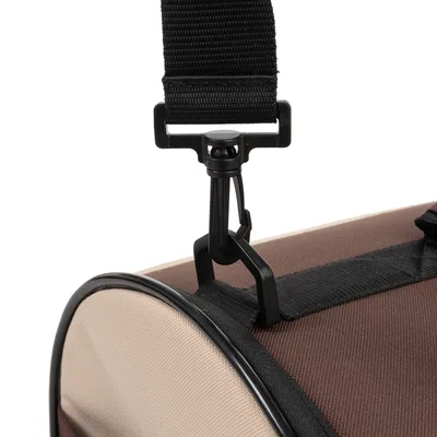 Gros plan sur l’attache en plastique noir et la sangle réglable d’un sac de transport pour animaux, tissu beige et marron visible.