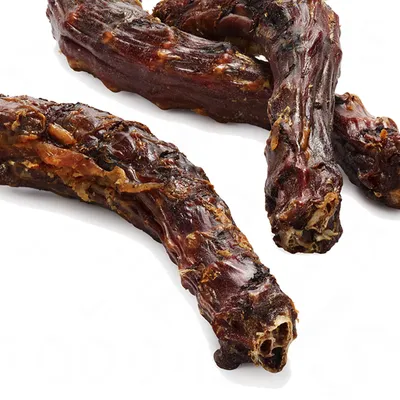 Torkade köttbitar med synliga ben, flera stycken på vit bakgrund. Ingen förpackning eller märkning synlig.