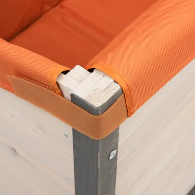Detailansicht eines Holzrahmens mit orangefarbenem Stoffbezug und Klettverschluss, befestigt an einer Ecke des Rahmens.