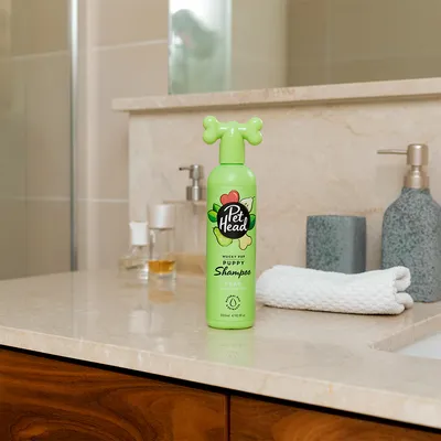 Pet Head Mucky Pup shampoo per cuccioli con profumo di pera, flacone da 300 ml, design verde con tappo a forma di osso.