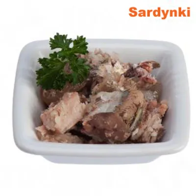 Sardynki w kawałkach podane w białej misce, udekorowane natką pietruszki. Widoczny napis: Sardynki.