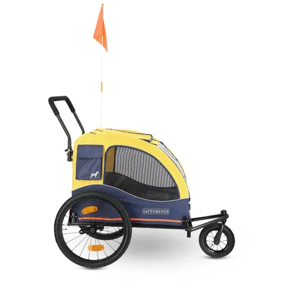 Yellow and blue dog trailer with mesh windows, orange safety flag and the inscription 'Hafenbande'.