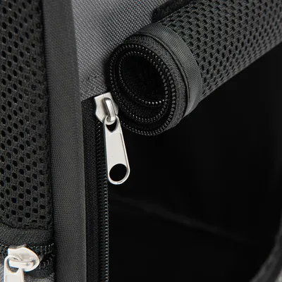 Dettaglio di una cerniera nera e materiale a rete su una borsa o trasportino.