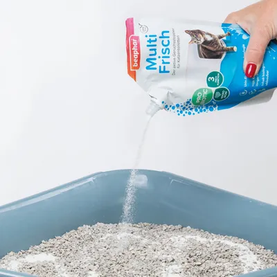 Beaphar Multi Frisch, Probiotic Katzenstreu-Zusatz wird in eine Katzentoilette gestreut. Verpackung zeigt Katze und Hinweise zu Geruchsneutralisierung und biologischer Abbaubarkeit.