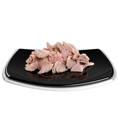 Zerkleinerte Stücke von hellem Fleisch auf einem schwarzen Teller, präsentiert als Produktinhalt.