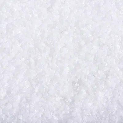 Witte korrelige substantie, close-up van grove kristallen. Materiaal: mogelijk mineraal of steenzout, geen merknaam of tekst zichtbaar.