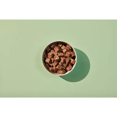 Bowl filled with small brown food cubes, shown from above to display product shape and size.