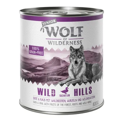 Boîte Wolf of Wilderness Senior Wild Hills 800 g, texte visible : 100% grain-free, canard & veau avec baies, racines et herbes sauvages. Image de loup sur fond de montagne.