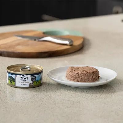 Boîte de pâtée pour animaux Ziwi Peak NZ Beef Recipe 92 % bœuf à côté d'une portion servie sur une assiette blanche, étiquette visible.
