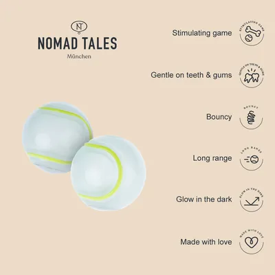 Nomad Tales München. Dos pelotas blancas con líneas verdes. Texto en inglés: estimulante, suave para dientes y encías, rebota, largo alcance, brilla en la oscuridad, hecho con amor.
