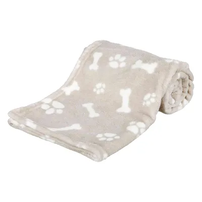 Manta beige de tela con dibujos blancos de huellas y huesos, enrollada parcialmente. Material tipo forro polar visible.