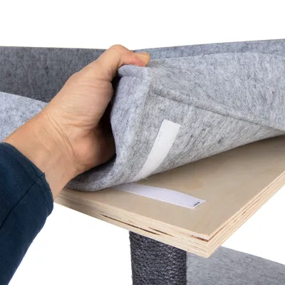 Hånd viser gråt filtbetræk med velcrolukning, der fastgøres til en træplade.