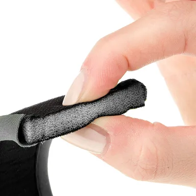 Zbliżenie palca ściskającego wyściełane wnętrze czarnego materiału, pokazujące miękką teksturę i elastyczność.