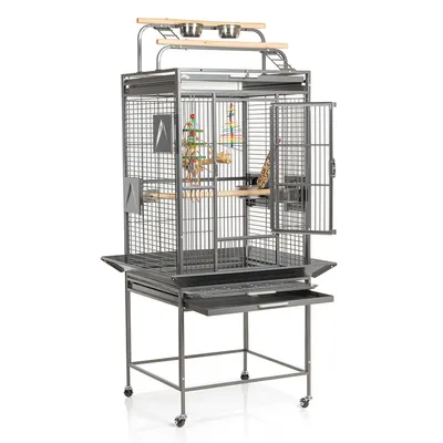 Grande cage à oiseaux en métal sur roulettes, perchoirs en bois, deux gamelles en acier inoxydable, jouets suspendus, porte ouverte et plateau amovible visible sous la cage.