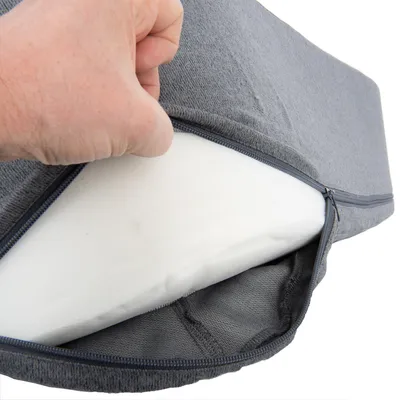 Hand öffnet grauen Bezug mit Reissverschluss, darunter sichtbarer weisser Schaumstoffkern.